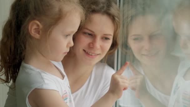 Close-up retrato da mãe com a filha sentada à janela . — Vídeo de Stock