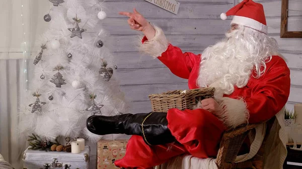 Santa is zittend in een stoel en speelgoed gooien — Stockfoto