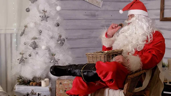 Père Noël est assis sur une chaise et jetant des jouets — Photo