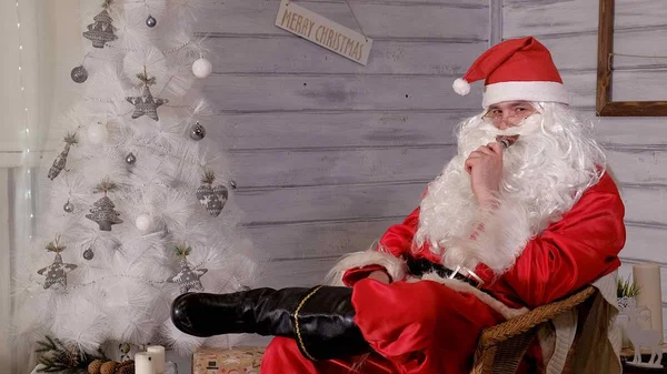 Papai Noel fuma limpar sentado em uma cadeira — Fotografia de Stock