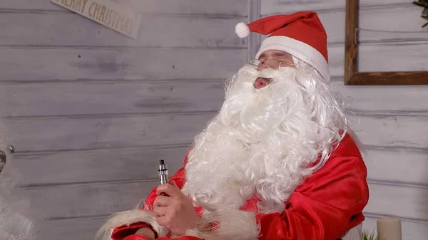 Santa rookt veeg zittend in een stoel — Stockfoto