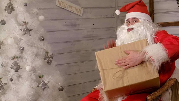 Santa está sosteniendo una gran caja de regalo en su mano —  Fotos de Stock