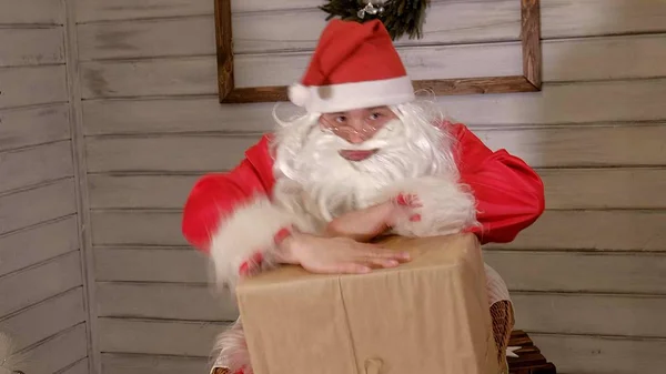 Santa håller en stor presentförpackning i handen — Stockfoto