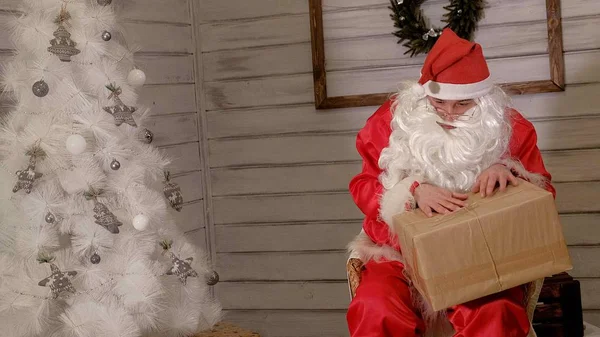 Santa is holding a big gift box in his hand — Stock Photo, Image