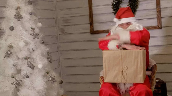 Papai Noel está segurando uma grande caixa de presente em sua mão — Fotografia de Stock