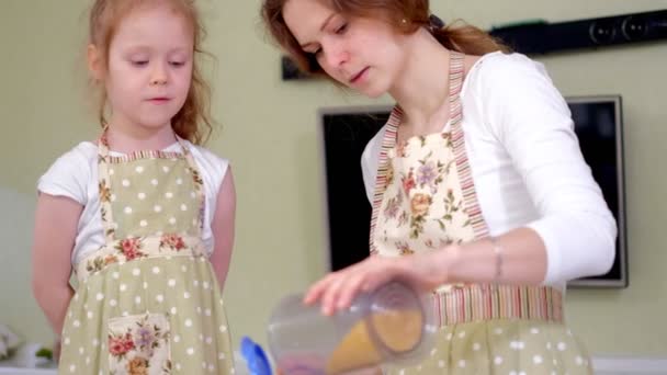 Jonge gelukkige moeder en haar schattige krullend peuter-daughterr in een keuken om te koken — Stockvideo