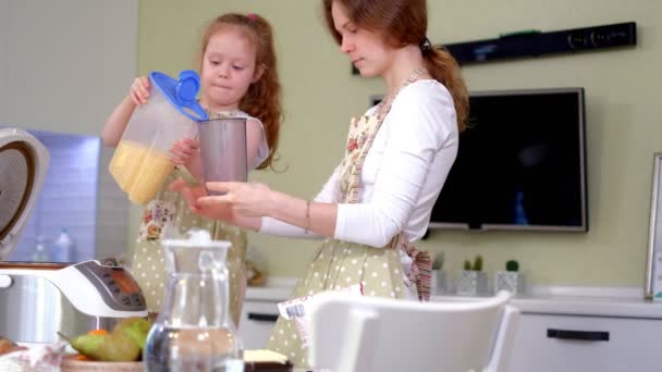 Joven madre feliz y su linda hija rizada en una cocina para cocinar — Vídeos de Stock