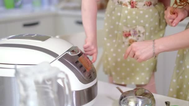 Joven madre feliz y su linda hija rizada en una cocina para cocinar — Vídeo de stock