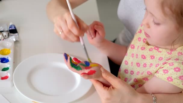 Famiglia felice, madre e bambina dipingono con le palme sui palmi delle mani — Video Stock