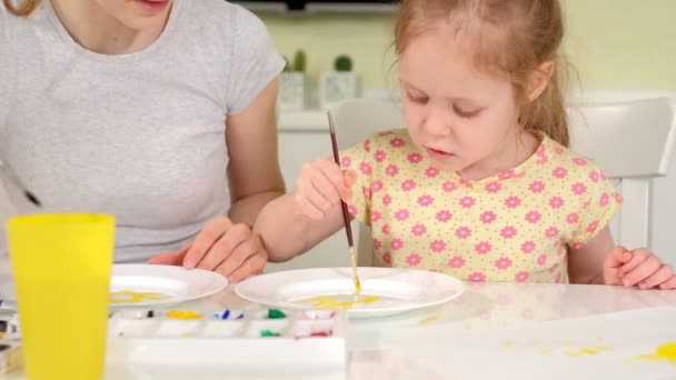 Happy family, mother and little daughter paint with paint on white plates — Stock Video