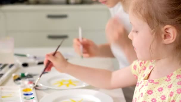 Familia feliz, madre e hija pequeña pintan con pintura en platos blancos — Vídeos de Stock