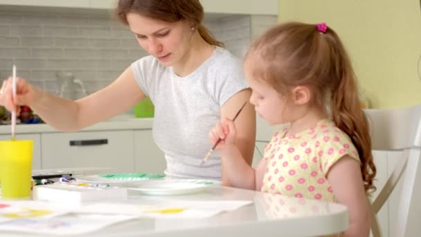 Familia feliz, madre e hija pequeña pintan con pintura en platos blancos — Vídeos de Stock