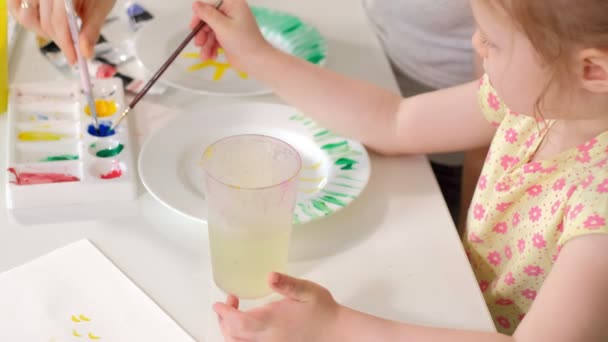 Familia feliz, madre e hija pequeña pintan con pintura en platos blancos — Vídeo de stock