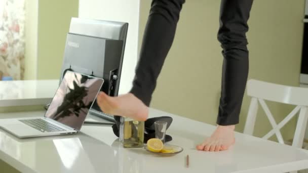 Uma mulher de negócios bêbada dança em uma mesa, em um computador de mesa e uma garrafa de alcagol — Vídeo de Stock