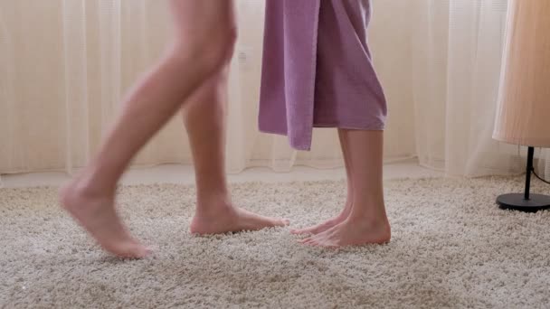 L'homme vient à la femme après la douche, la serviette tombe au sol, pieds gros plan — Video