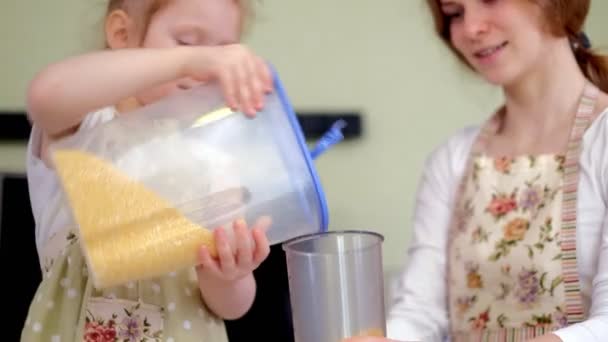 Young happy mother and her cute curly toddler daughterr in a kitchen to cook — Stock Video