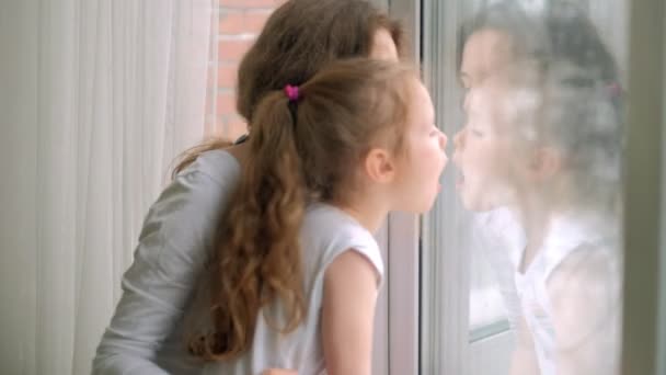 Close-up retrato da mãe com a filha sentada à janela . — Vídeo de Stock