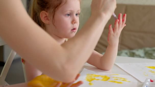 Glückliche Familie, Mutter und kleine Tochter malen mit Palmen auf ihren Handflächen — Stockvideo