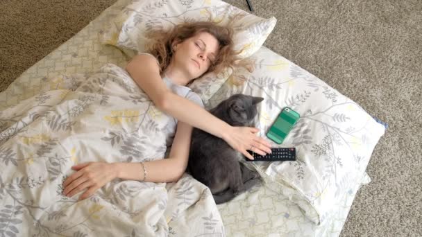 Спляча з кішкою, жінка прокидається від дзвінка, що тягне за телефон — стокове відео