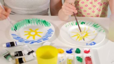 Mutlu aile, anne ve küçük kızı boya boya beyaz plakaları ile