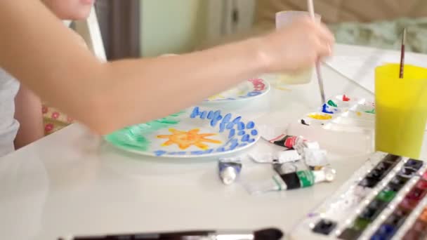 Glückliche Familie, Mutter und kleine Tochter malen mit Farbe auf weißen Tellern — Stockvideo