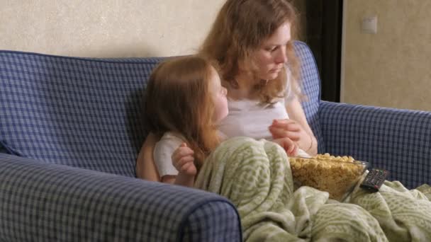 Feliz família amorosa. A mãe e a filha estão a comer pipocas na cama do quarto. frente da TV — Vídeo de Stock