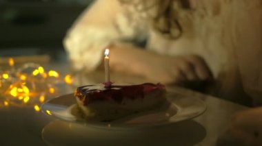 Lezzetli doğum günü pastası ile plaka karşı ufuk ışık tutan genç kadın bir mumu darbeler