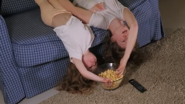Glückliche liebende Familie. Mutter und Tochter essen Popcorn auf dem Bett im Zimmer. vor dem Fernseher — Stockvideo