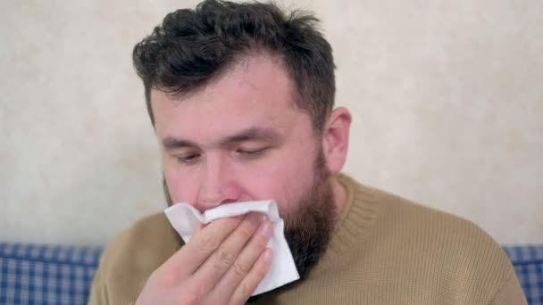 Hälso-och sjukvård, influensa, hygien och människor koncept - sjuka man blåser näsan till pappers servett hemma — Stockvideo