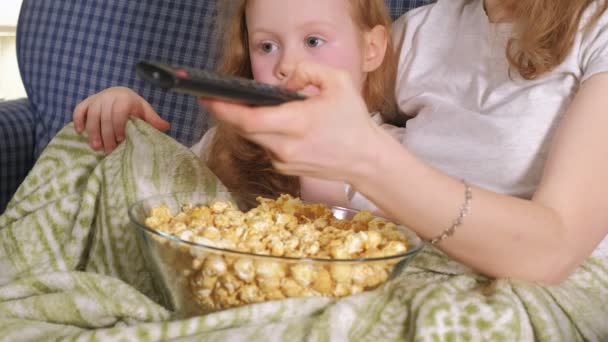 Szczęśliwy, kochającą rodzinę. Matka i jej córka dziecko dziewczynka jedzą popcorn na łóżku w pokoju. przodu telewizora — Wideo stockowe