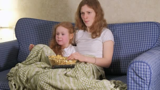 Glückliche liebende Familie. Mutter und Tochter essen Popcorn auf dem Bett im Zimmer. vor dem Fernseher — Stockvideo