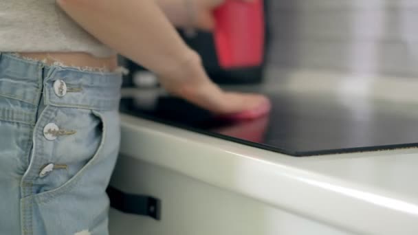 Žena čištění kuchyňské skříňky s houbou a sprej čistič.