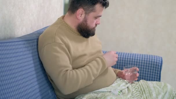 Mann trinkt Wasser mit Tabletten, sitzt im Bett. — Stockvideo