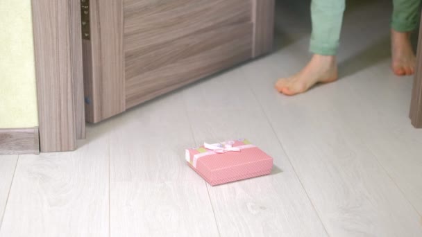 Женщина находит подарок под дверью — стоковое видео