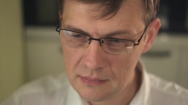 Ein junger Mann mit Brille, der einen Computer benutzt, schaut, studiert. Nahaufnahme — Stockvideo