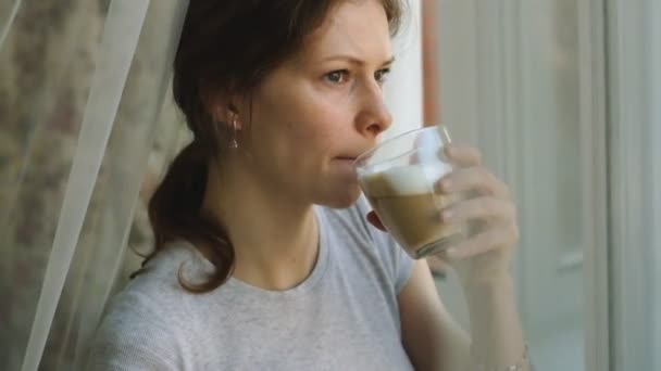 Jong meisje met sproeten cappuccino drinken en eten van een cake — Stockvideo