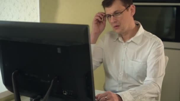 불만을 품은 젊고 잘생긴 남자 가 직장에 앉아서 안경을 들고 기진맥진해 있는 모습 — 비디오