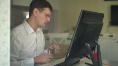 Beyaz tişörtlü içme alkol, gergin adam bilgisayarda ev ofis, stres içinde çalışan