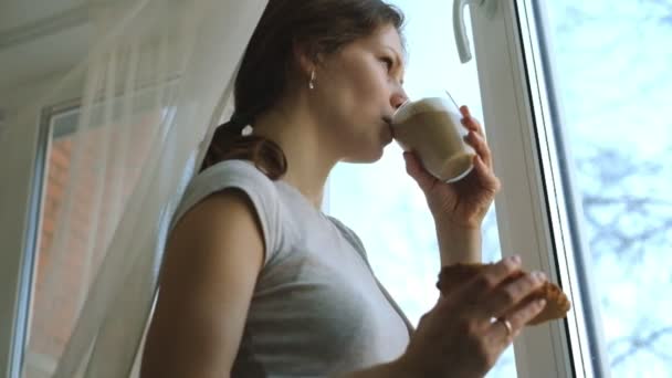 Junges Mädchen mit Sommersprossen trinkt Cappuccino und isst einen Kuchen — Stockvideo