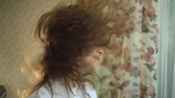 Ragazza capelli ricci, gira attivamente la testa, giocoso, ascolta la musica nelle cuffie alla finestra, ballare, cantare. ritratto — Video Stock