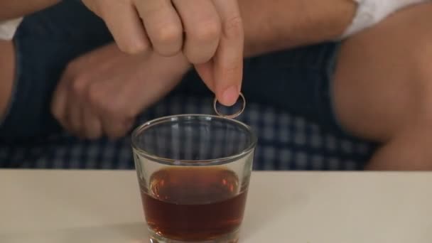 Man in right hand flask with alcohol, in left engagement ring. thinks, divorce. close-up — Stock Video