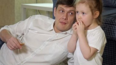 adam ve televizyon izlerken, abur cubur yeme katta oturan kızı