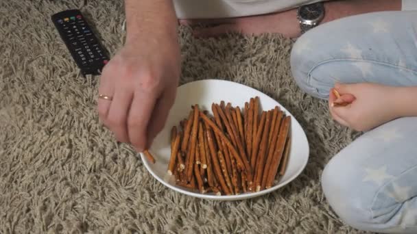 Ember és lánya tévénézésre, ült a földön enni snack — Stock videók