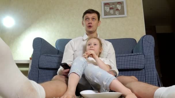 男人和女儿看电视, 坐在地板上吃零食 — 图库视频影像