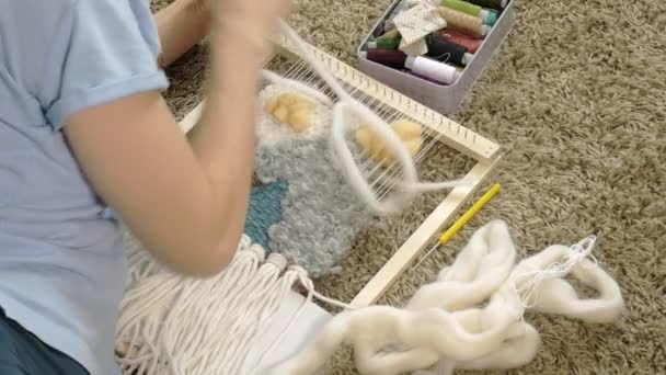 En kvinna väver på en vävstol en vackra broderier gjort av garn, i en hemmastudio, — Stockvideo