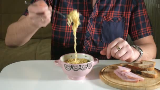 El hombre está comiendo fideos instantáneos chinos con un tenedor — Vídeos de Stock