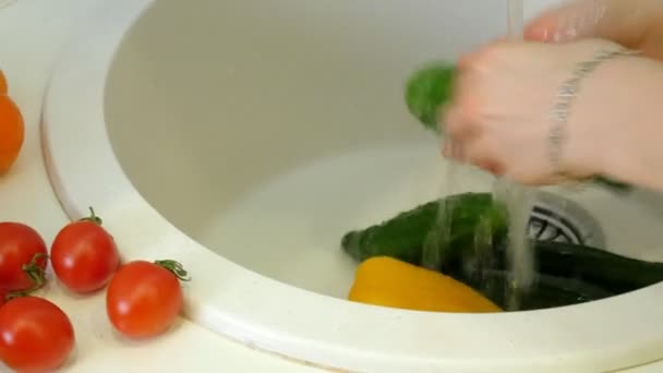 女性は、台所の流しの蛇口の下で新鮮な野菜を洗う — ストック動画