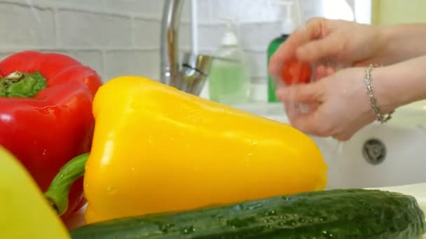 Mujer lava verduras frescas bajo el grifo en el fregadero en la cocina — Vídeo de stock