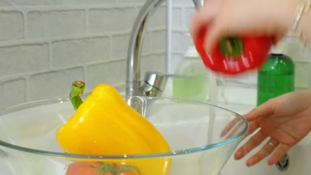 Mujer lava verduras frescas bajo el grifo en el fregadero en la cocina las pone en una taza de vidrio — Vídeo de stock