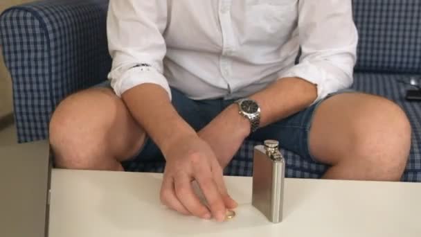 Man in right hand flask with alcohol, in left engagement ring. thinks, divorce. close-up — Stock Video